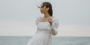 Foto de mulher de vestido branco longo em frente a praia