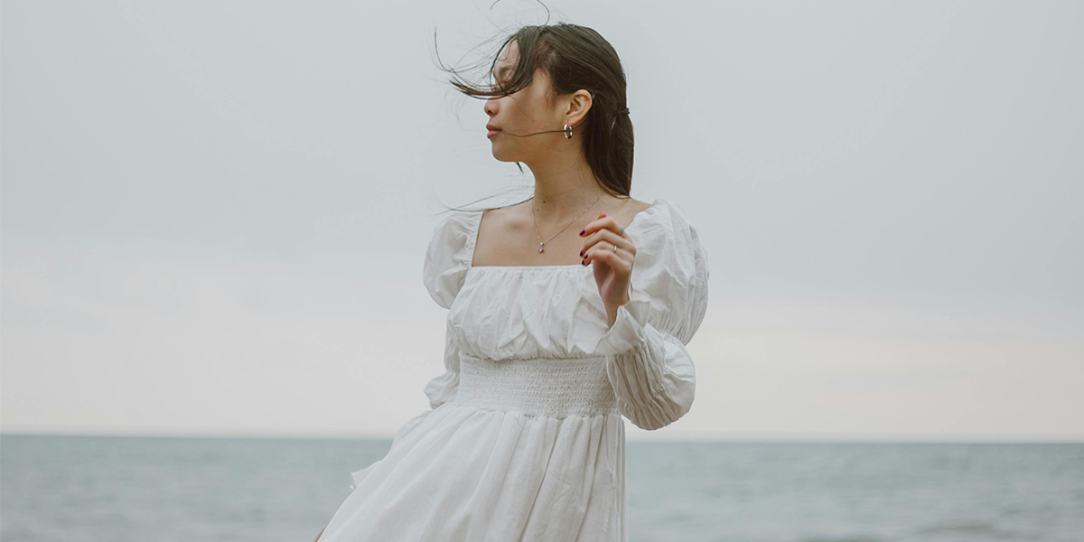 Foto de mulher de vestido branco longo em frente a praia