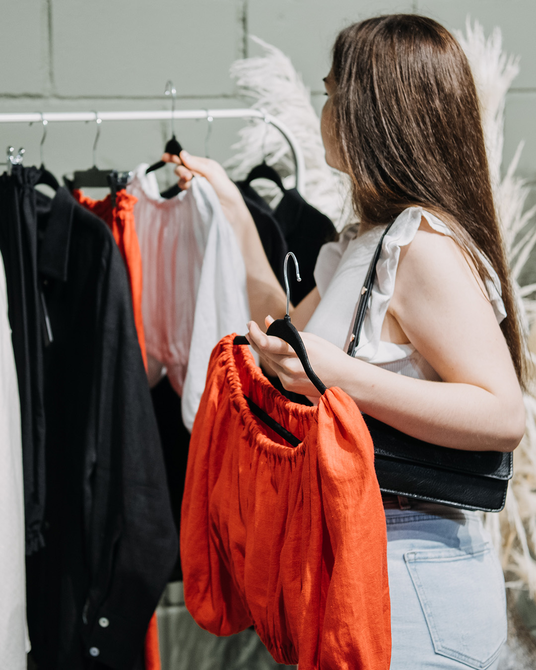 Foto de modelo escolhendo roupas de uma loja slow fashion